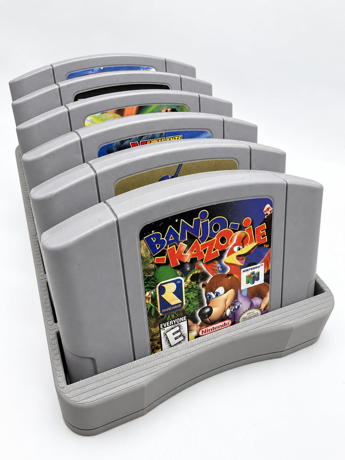 Gray six-slot N64 cartridge holder displaying six Nintendo 64 games, viewed from the front at a three-quarter angle.