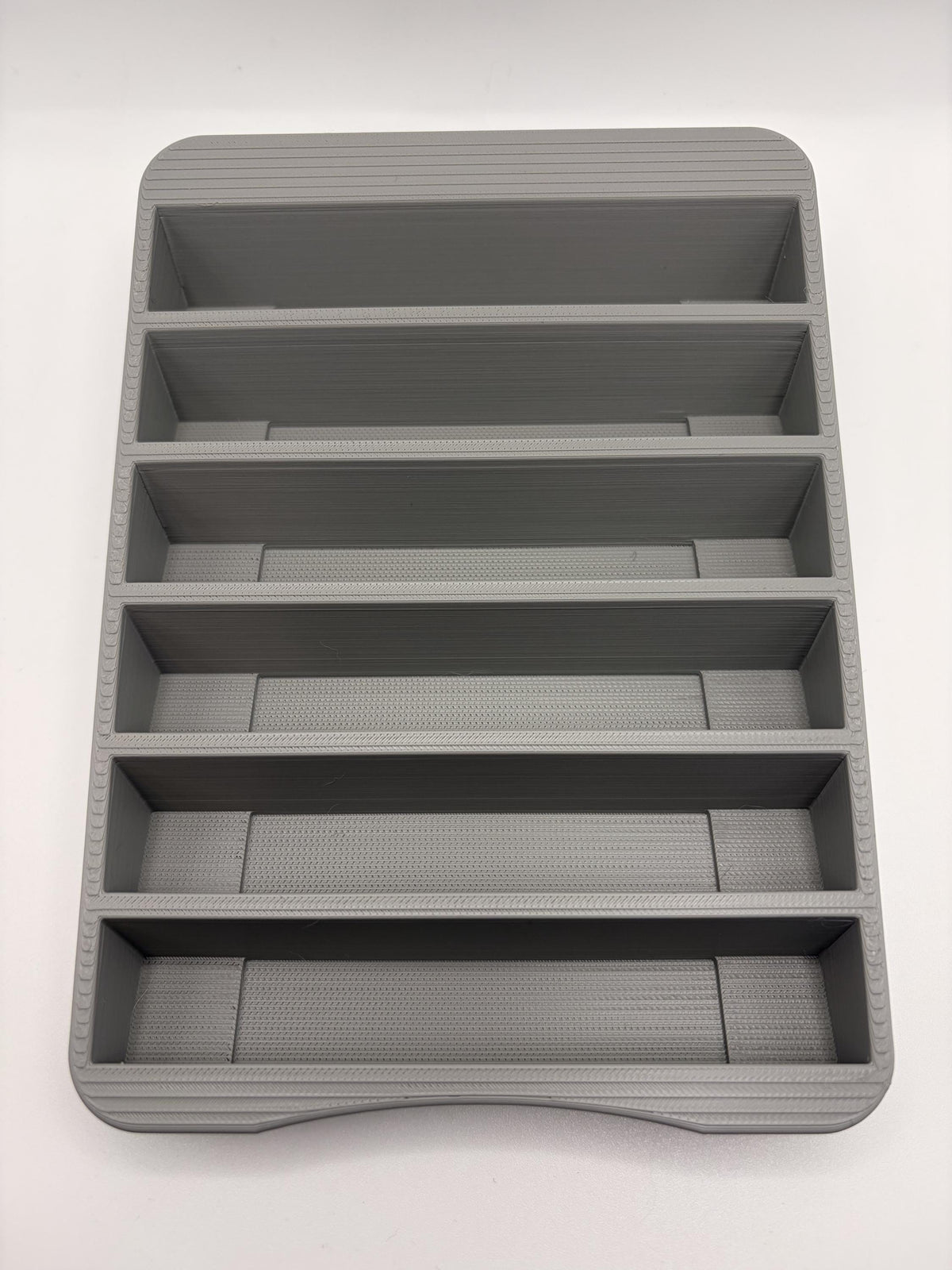 Empty gray N64 holder viewed from above, showing six separate cartridge pockets and the curved front edge.