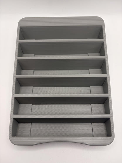 Empty gray N64 holder viewed from above, showing six separate cartridge pockets and the curved front edge.