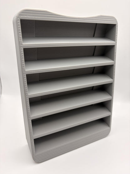 Angled view of the empty six-slot gray holder, showing the cartridge pockets and visible 3D print layer lines.