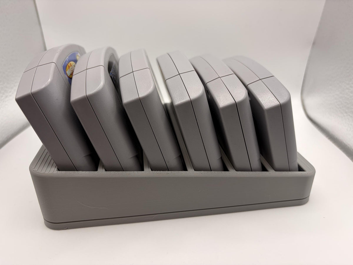 Side view of six Nintendo 64 cartridges leaning backward in the gray display holder.