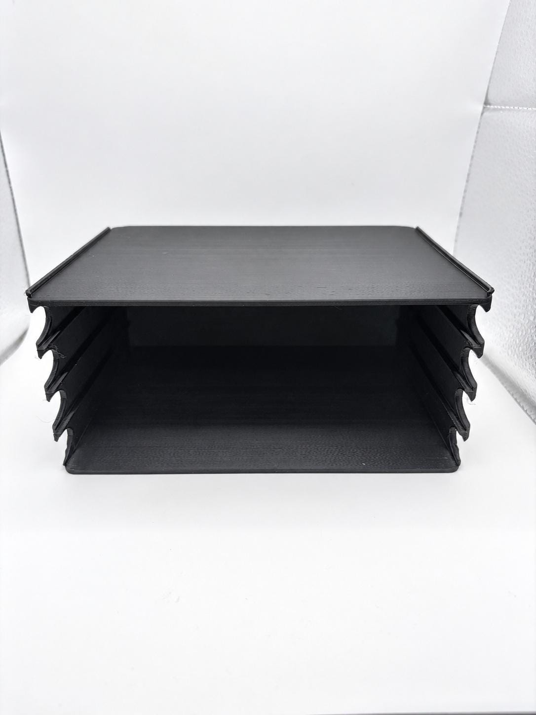 Close-up of the empty black holder showing four horizontal lanes and front finger scoops.