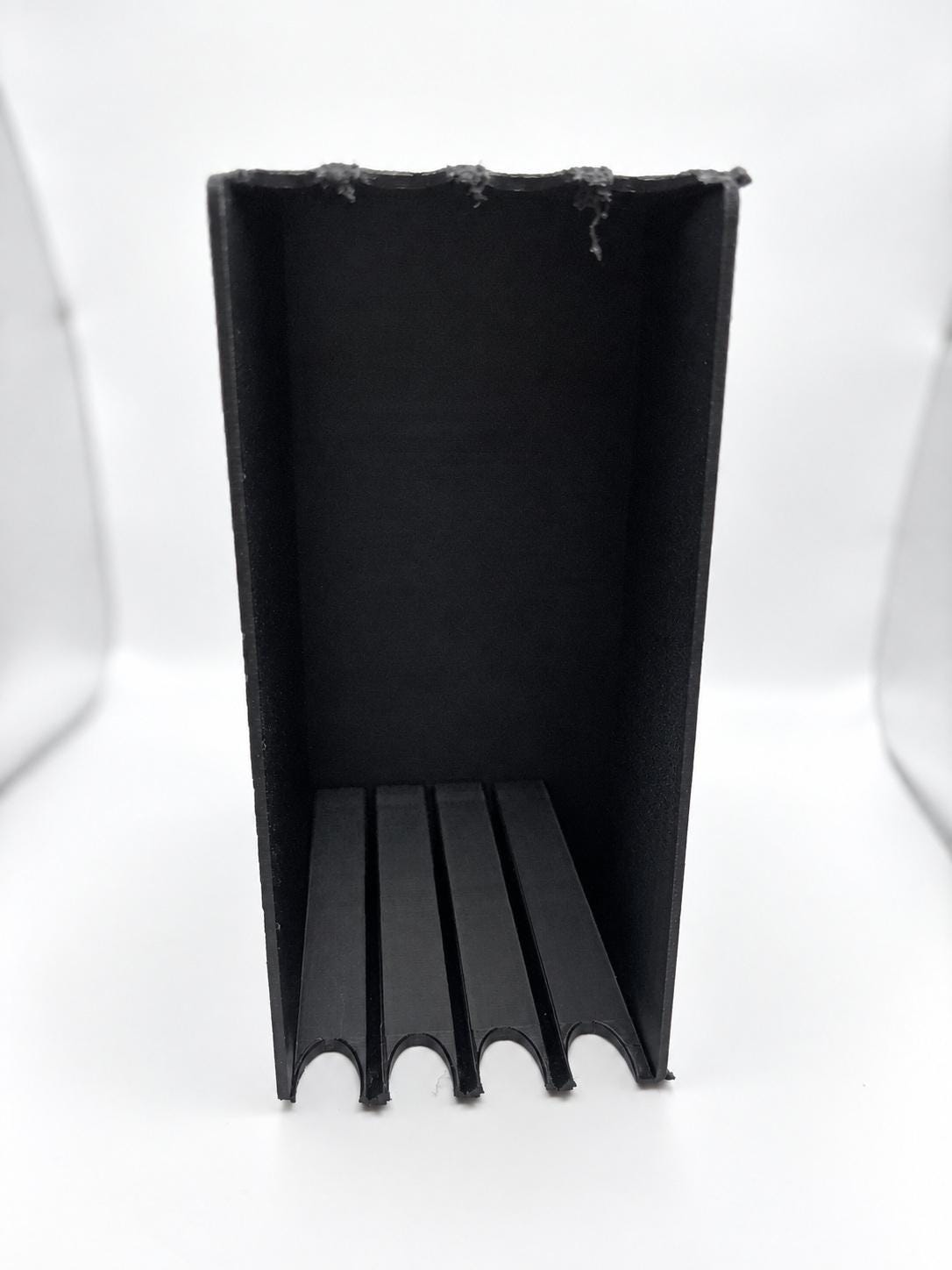 Empty black four-slot holder turned onto its side for vertical case storage.