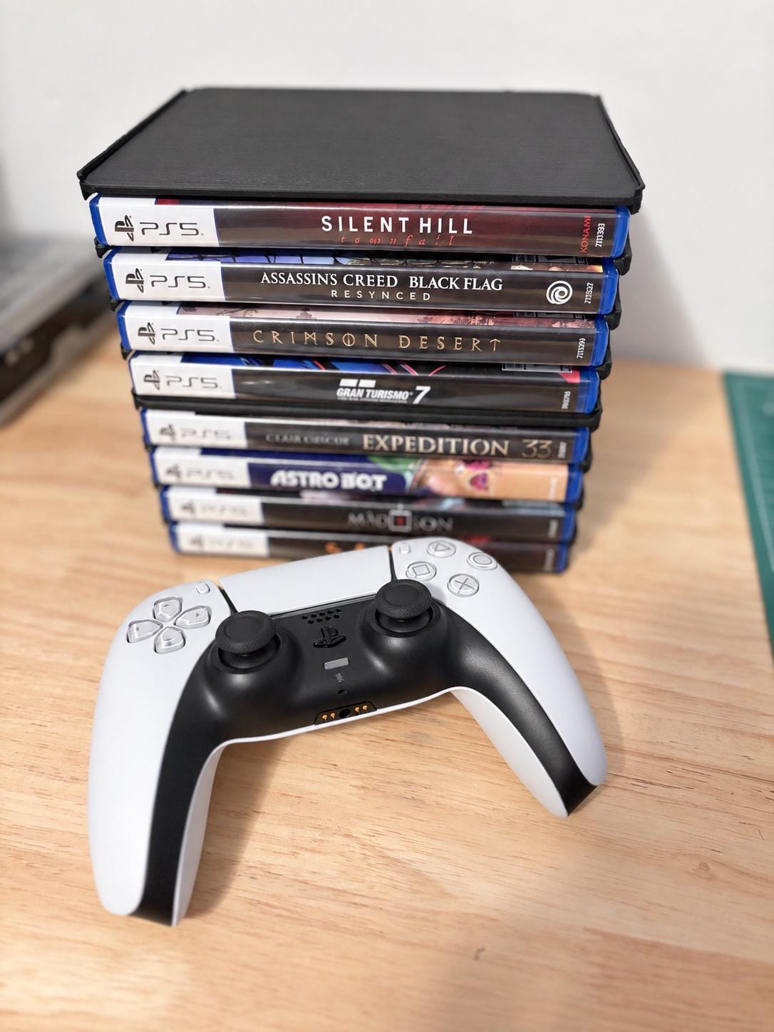 Two horizontally stacked holders on a wooden surface with a controller in front for scale; games and controller not included.
